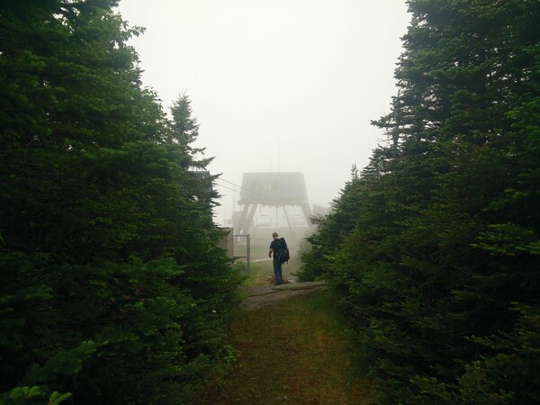 A figure hikes toward the top of the Cannon Mountain Aerial Tramway, obscured by fog