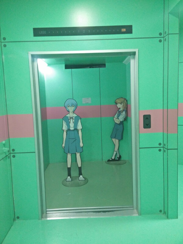 Cutouts of Asuka and Rei in the famous elevator still frame from Neon Genesis Evangelion